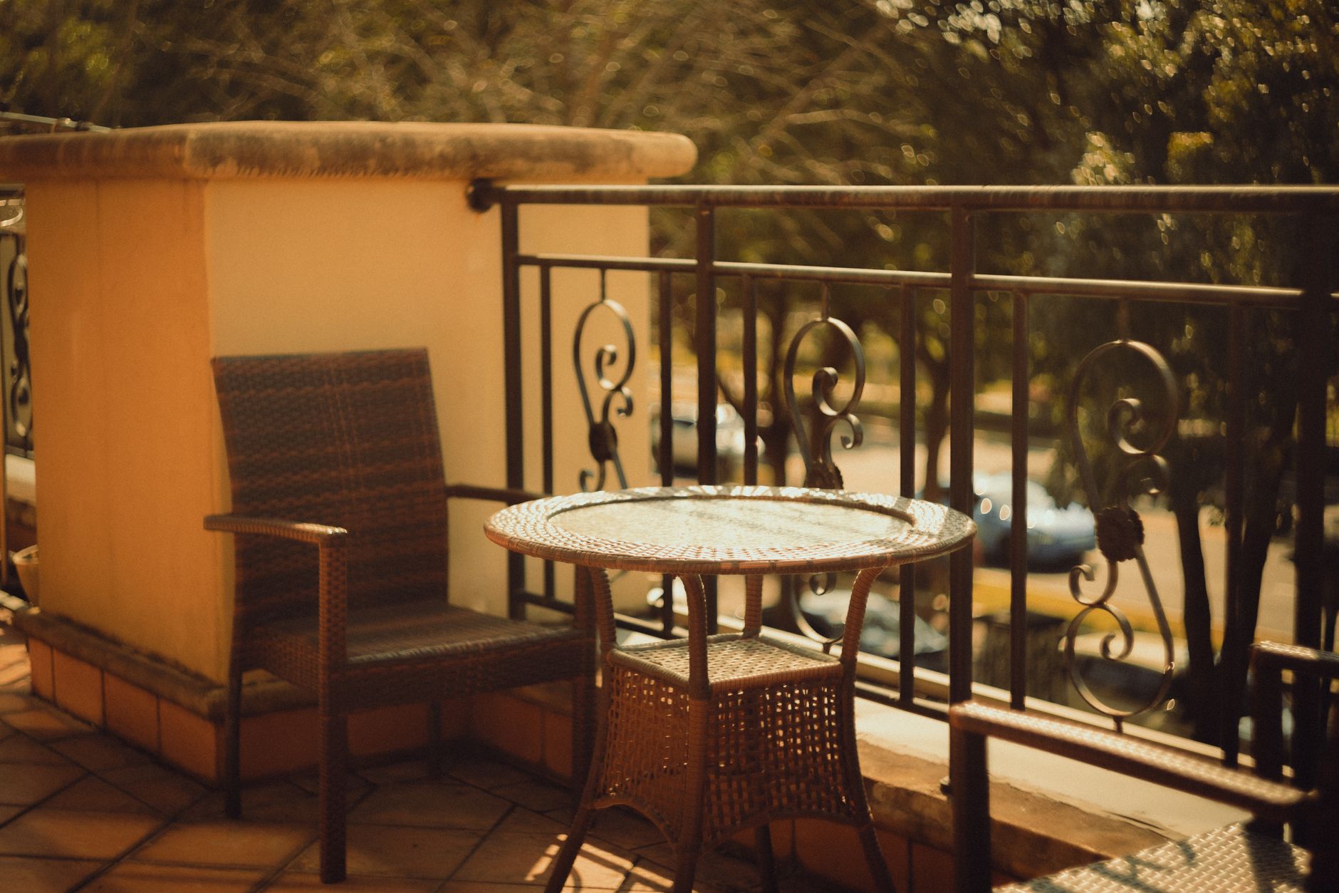 a sun-drenched private villa terrace overlooking a tropical coastline, with an empty lounge chair and a small side table holding a drink, no people visible