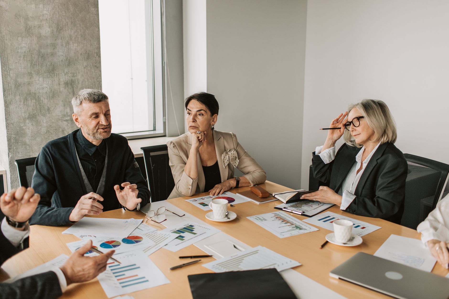 a quiet wealth management office interior with a polished conference table, legal documents fanned out, and large windows overlooking a city skyline at midday